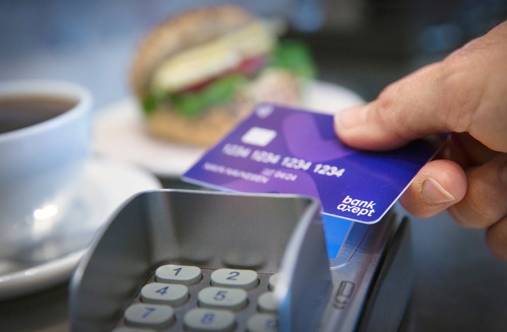 Person betaler ved å tæppe kort på betalingsterminal